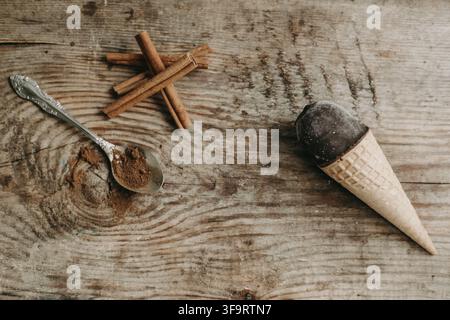 Schokoladeneis in einer Waffel auf einem Holz-Hintergrund. Süßes Dessert auf dem Tisch. Komposition mit Eis Süßer Snack. Eis mit Zimt und Stockfoto