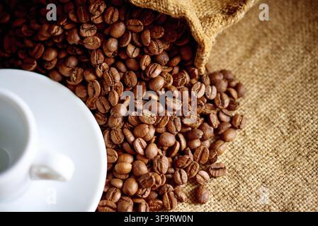 Weiße Tasse und Kaffeebohnen auf Sackleinen mit Platz für Text Stockfoto