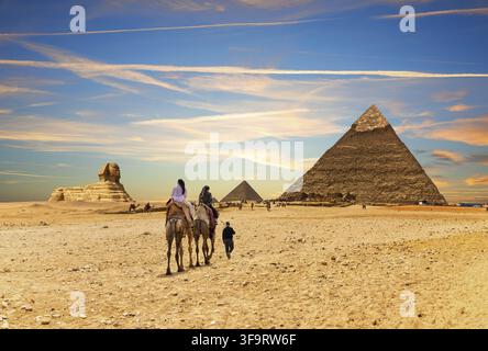 Touristen auf Kamelen mit beduinen vor den Großen Pyramiden von Ägypten, Gizeh Stockfoto