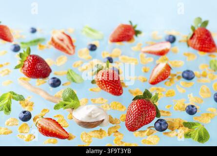 Konzept eines gesunden glutenfreien Frühstücks mit Beeren, Naturjoghurt und Cornflakes auf blauem Hintergrund Stockfoto