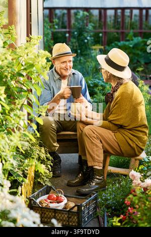 Seniorenpaar trinkt Kaffee und unterhält sich im Garten Stockfoto
