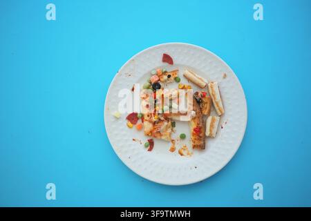 Pizzareste auf einem weißen Teller auf blauem Hintergrund Stockfoto