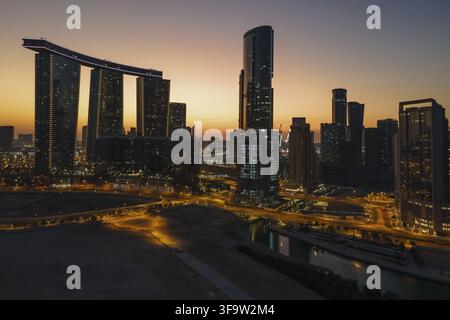 Zauberhafter Sonnenuntergang auf der Insel Al Reem in Abu Dhabi. Luftaufnahme der silhouettierten modernen Wolkenkratzer. Stockfoto