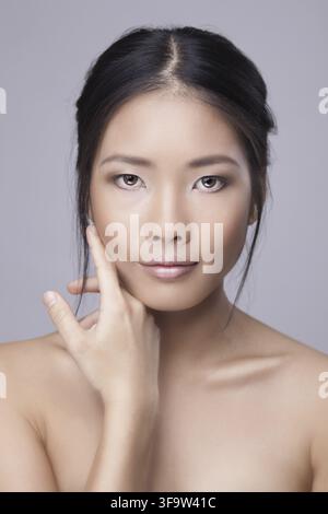 Asiatische Schönheitspflegefrau, die perfekte Haut im Gesicht berührt. Schönes Wellness-Beauty-Pflege- und Spa-Konzept mit multiethnischem chinesisch-thailändisch-asiatischem Mädchen Stockfoto