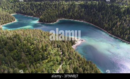 Luftaufnahme eines malerischen türkisfarbenen Sees mit kleinen Buchten und dichtem Kiefernwald, aufgenommen an einem sonnigen Tag Stockfoto