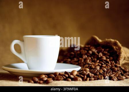 Weiße Tasse und Kaffeebohnen auf einem unscharfen Hintergrund Stockfoto
