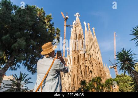 Reisefrau macht mit dem Smartphone ein Foto der Sagrada Familia Kathedrale in Barcelona an einem sonnigen Tag Stockfoto