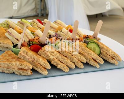 Verschiedene Fingersandwiches und kleine Vorspeisenbecher, die auf einem Tisch serviert werden. Stockfoto