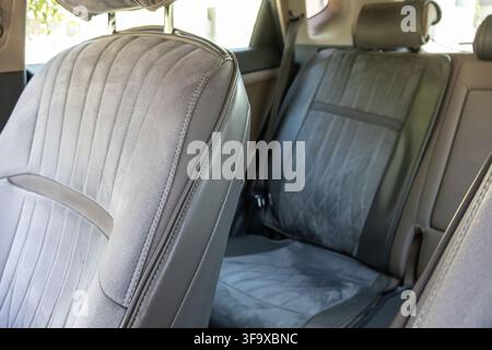 Innenansicht, die sich auf leere graue Stoffrücksitze für Passagiere mit Sicherheitsgurten und Kopfstützen in einem sauberen modernen Automobil konzentriert. Stockfoto