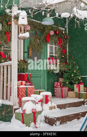 Schneebedeckte Weihnachtsgeschenke auf einer geschmückten Veranda Stockfoto