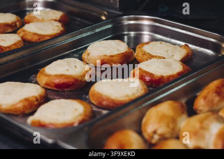 Leckere frisch gebackene, aromatische Brötchen aus süßem Teig, die auf einem großen Metallgericht in der Bäckereiküche stehen. Sieht köstlich aus, lecker. Layi Stockfoto