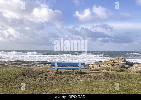 Mächtige Atlantikwellen schlagen gegen felsige Klippen entlang der Küste der Bretagne in Frankreich. Unter einem strahlend blauen Sommerhimmel glitzern das Meer und die schroffe Küste Stockfoto
