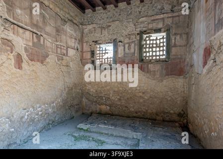 Freskiertes Wohnraum mit architektonischen Wandgemälden und zwei Gitterfenstern im Haus des Holzschirms im Archäologischen Park von Hercu Stockfoto