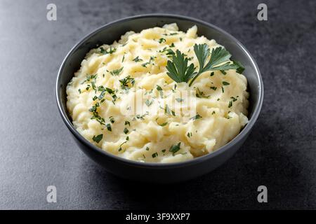 Schüssel mit cremigen hausgemachten Kartoffelpüree, garniert mit frischer Petersilie auf einem dunklen Hintergrund Stockfoto