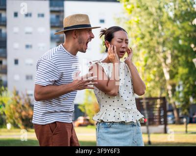 Frustriertes Paar streitet sich, während es an einem sonnigen Tag zusammen in einem Wohnpark steht. Stockfoto