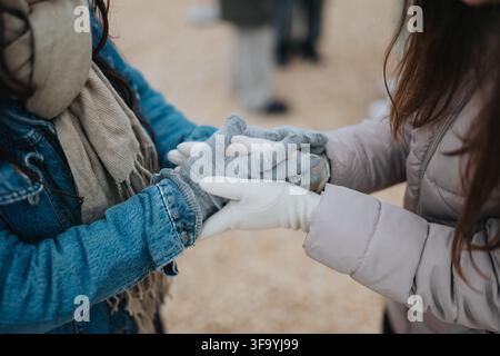 Zwei Personen, die sich während des Winters im Freien an den Händen halten und Wärme sowie sanfte Unterstützung teilen Stockfoto
