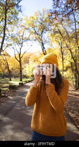 Frau macht Fotos mit einer Vintage-Kamera in einem Herbstwald Stockfoto