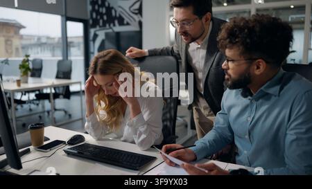 Drei gestresste, problembeladene multikulturelle Bürokollegen, die auf den Laptop schauen, reden, streiten, ein Problem diskutieren, Misserfolg, Online-Arbeit, Vielfalt Stockfoto
