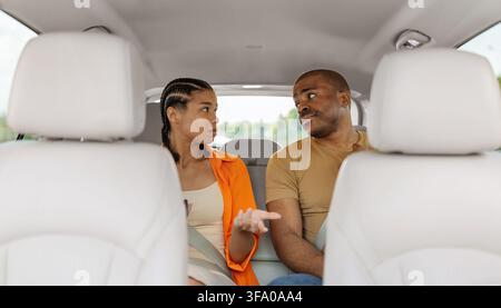 Junges schwarzes Paar führt ein ernstes Gespräch, während es im Auto sitzt Stockfoto