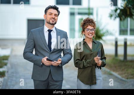 Geschäftskollegen gehen im Freien, lächeln und kommunizieren Stockfoto