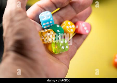 Hohe Winkelaufnahme einer Hand, die rote, blaue, grüne und gelbe Würfel für Glücksspiele hält Stockfoto