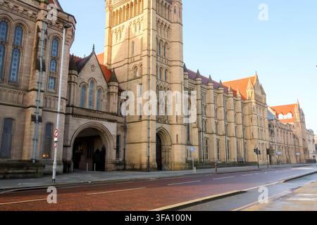Sonnendurchflutete Ansicht der historischen gotischen Gebäude der Manchester University entlang der Oxford Road in Manchester, England, mit verzierten Steinfassaden, Türmen, Bogen Stockfoto