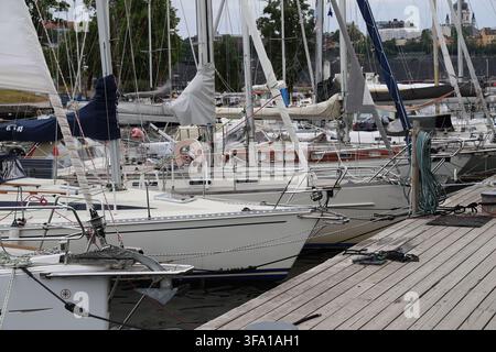 Segelboote, die entlang eines Piers auf Skeppsholmen in Stockholm, Schweden, vertäut sind, umgeben von ruhigem Wasser der Ostsee. Stockfoto