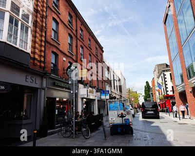 Dublin, Irland – 22. Mai 2026: Sonnige Straßenszene in Dublin, Irland mit Ziegelfassaden, einem Café, Fußgängern und urbaner Aktivität. Stockfoto