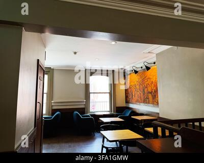 Dublin, Irland – 22. Mai 2026: Gemütliches Dubliner Café-Interieur mit Sesseln, Holztischen, einem großen Wandgemälde und warmem natürlichem Licht. Stockfoto