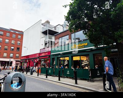 Dublin, Irland – 22. Mai 2026: Kunden entspannen sich auf den Außensitzen von Handsome Burger und Metro Cafe in einer belebten Straße in Dublin. Stockfoto