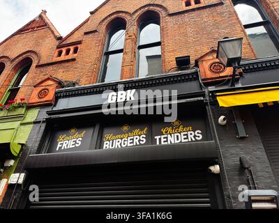 Dublin, Irland – 22. Mai 2026: Vorderansicht des GBK-Burgerrestaurants in Dublin mit Ziegelarchitektur, Beschriftung und geschlossenem schwarzen Rollladen. Stockfoto