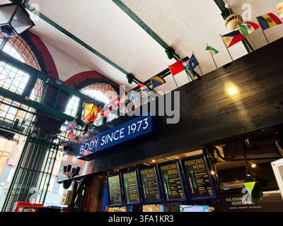 Dublin, Irland – 22. Mai 2026: Schaufenster eines Innenmarkts mit einem auffälligen Schild „Body Since 1973“, Piercing-Menü und internationalen Flaggen. Stockfoto