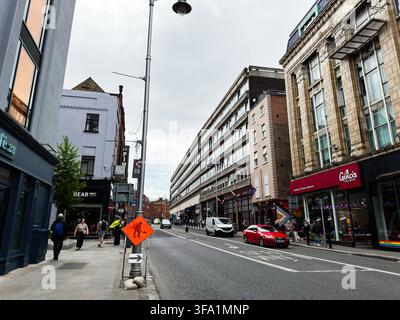 Dublin, Irland – 22. Mai 2026: Belebte Dubliner Straße mit Geschäften, Fußgängern und Autos, eingerahmt von moderner und historischer Architektur. Stockfoto