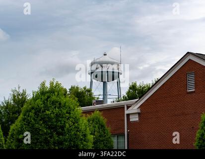 Urban und Infrastruktur: Erhöhter Stahl-Wasserturm mit Perry-City-Logo hinter einem Backsteingebäude und Grünflächen in Perry, Georgia Stockfoto