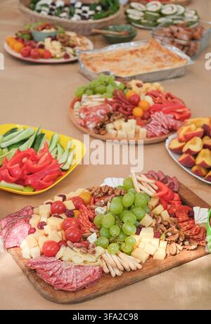 Festlicher Buffettisch mit einer großen Platte mit Aufschnitt, frischem Gemüse, Obst, Käse und verschiedenen Vorspeisen, vorbereitet für eine Essensparty Stockfoto