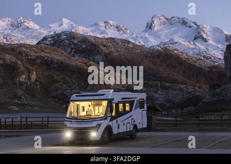 Blick auf ein modernes Wohnmobil, das in der Nähe der Seen von Covadonga geparkt ist, mit schneebedeckten Bergen im Hintergrund bei Dämmerung in Asturien, Spanien. Stockfoto