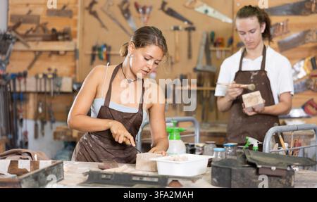 Der Kerl ist in einer Tischlerei mit einer Unternehmerin beschäftigt Stockfoto