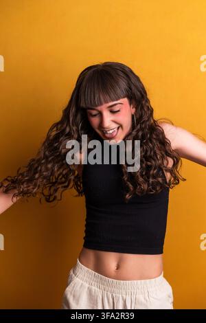 Fröhlicher junger Tänzer performt mit Energie auf gelbem Hintergrund Stockfoto