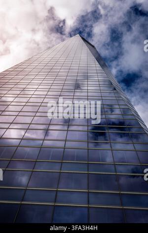 Niedrigwinkelaufnahme einer reflektierenden Glasfassade eines Wolkenkratzers mit in den Fenstern gespiegelten Wolken Stockfoto