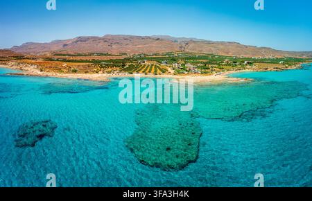 Luftpanorama der Küste von Xerokambos mit türkisfarbenem Meer, sandigem Strand, Küstendorf und landwirtschaftlichen Feldern vor trockenen Bergen im Südosten Stockfoto