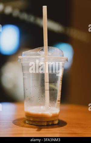 Leere Starbucks-Eiskaffeetasse mit Strohhalm auf Holztable in einem Café, verschwommene Hintergrundlichter — Stockfoto