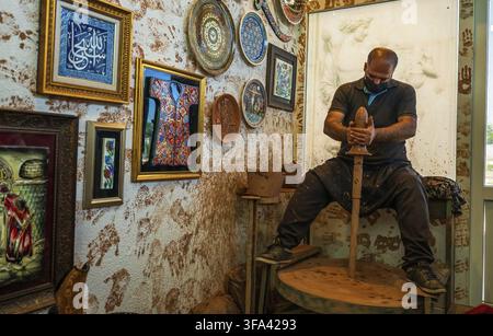 Kappadokien, Türkei - 14. September 2021: Ein geschickter Handwerker formt Keramik auf einem Rad in einem Atelier, das mit lebhaften Kunstwerken und ethnischer Einrichtung geschmückt ist, Highli Stockfoto