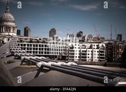 Stadtgebäude mit Kuppel, Brücke und Kränen vor einem klaren Himmel, Blick auf die Themse und die Londoner Skyline von der Millennium Bridge, Thames Embankment Stockfoto