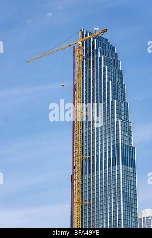 Vertikalausrichtung Foto von gelbem Turmkran neben moderner Glasfassade des im Bau befindlichen Wolkenkratzers 400 Lake Shore Drive Stockfoto