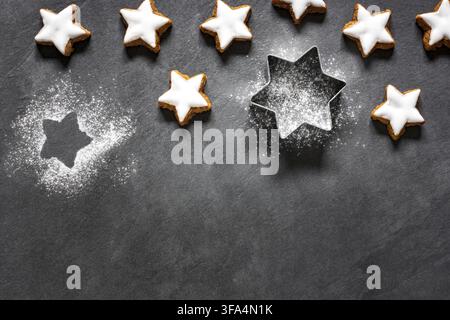 Frische zimtfarbene sternförmige Kekse mit Glasur auf Holztablett Stockfoto
