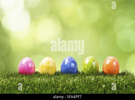 Eine Reihe von fünf bunten Ostereiern auf grünem Gras im Frühling Stockfoto