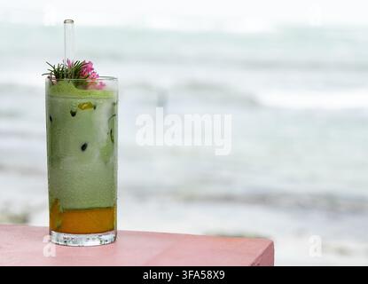 Eisgekühlter Matcha-Latte mit Mango auf einem rosa Strandtisch in Costa Rica Stockfoto