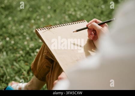 Frau zeichnet in einem Skizzenbuch im Freien während eines Kunst-Meisterkurses Stockfoto