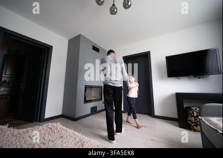 Zwei Geschwister teilen einen verspielten Moment, tanzen zusammen in ihrem schön gestalteten Wohnzimmer, das von Wärme und Licht erfüllt ist, und fangen die Freude des Kindes ein Stockfoto