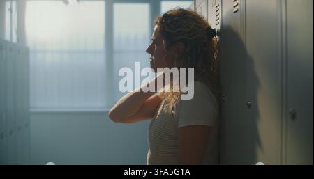 Lehrerin findet eine ruhige Pause im leeren Umkleideraum der Schule, schafft mentalen Freiraum nach der Unterstützung von Schülern den ganzen Tag. Emotionale Erholung, Achtsamkeit bei der Arbeit, nachhaltiges Lehren. Stockfoto